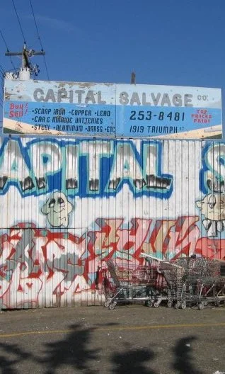 A wall with graffiti that says "Capital Salvage"