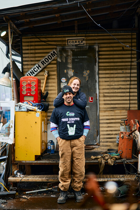 A man and a woman pose in front of a house