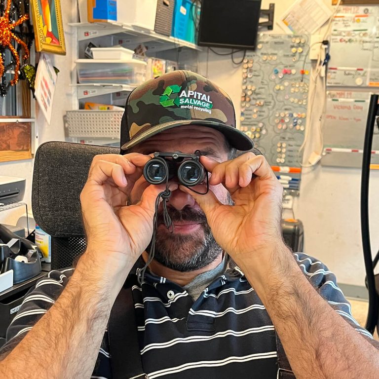 A man holds a pair of tiny binoculars up to their face